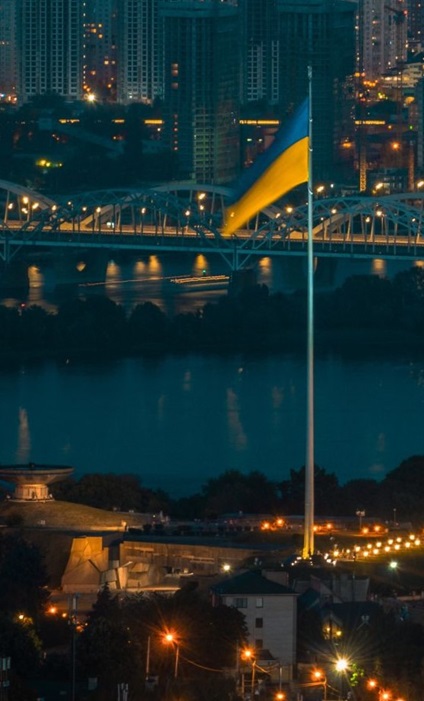 Kyiv skyline at night with the Ukrainian flag and the Motherland Monument overlooking the Dnipro River, symbolizing Hogan Lovells’ landmark High Court victory for PrivatBank in its $2 billion fraud case.